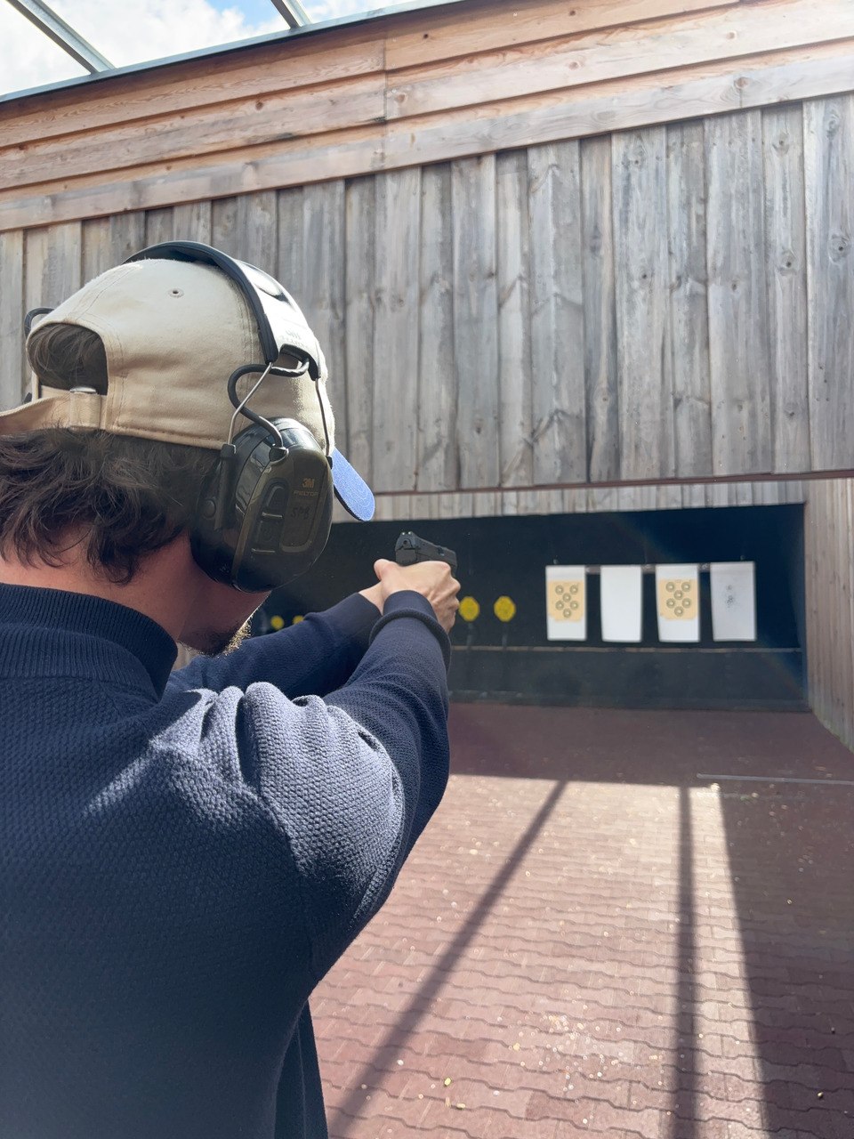 Teilnehmer mit Gehörschutz schießt auf der Schießstätte mit einer Kurzwaffe auf Scheiben